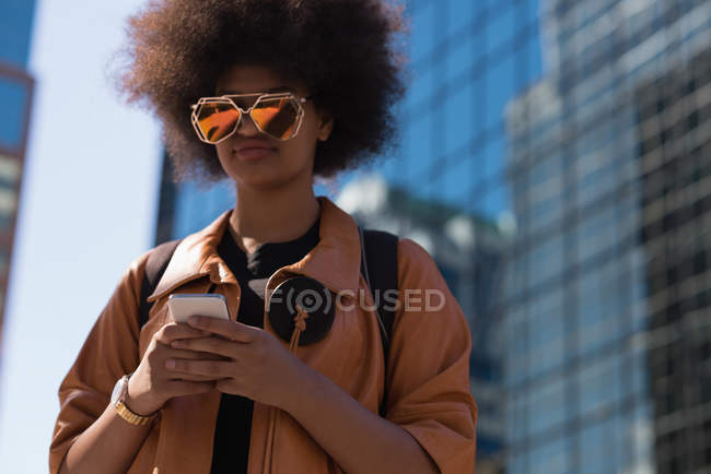 Mujer usando teléfono móvil en la ciudad en un día soleado - foto de stock