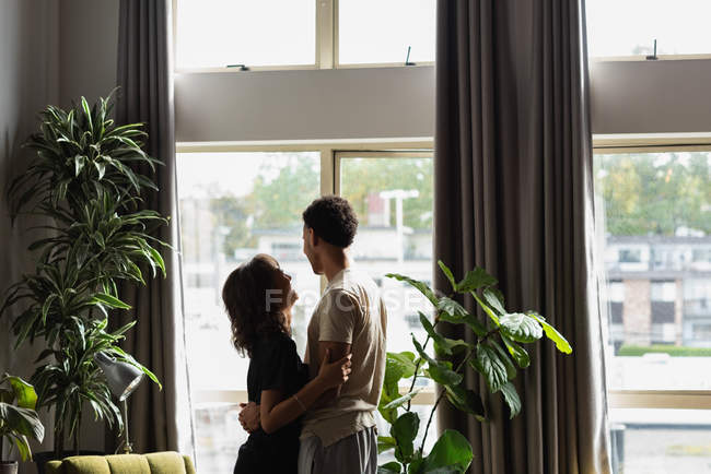 Пара дивлячись через вікно у вітальні на дому — стокове фото