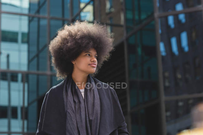 Mujer afro reflexiva caminando por la calle - foto de stock