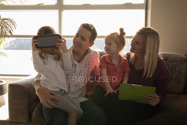 Menina usando fone de ouvido realidade virtual com a família na sala de estar em casa — Fotografia de Stock