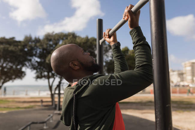 Young man doing pull ups in garden — Stock Photo