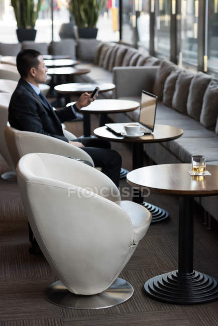 Businessman using mobile phone on sofa in hotel — Stock Photo