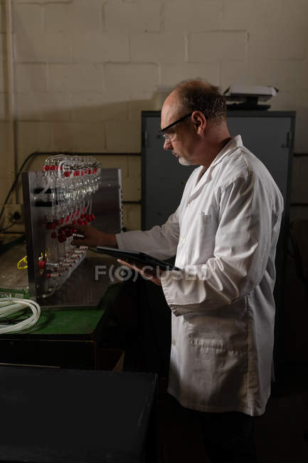 Чоловік працює під час використання цифрового планшета на заводі — стокове фото
