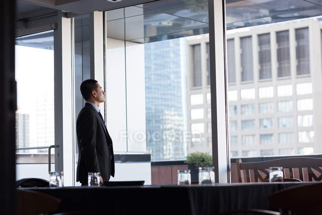 Businessman looking through window in conference room at hotel — Stock Photo