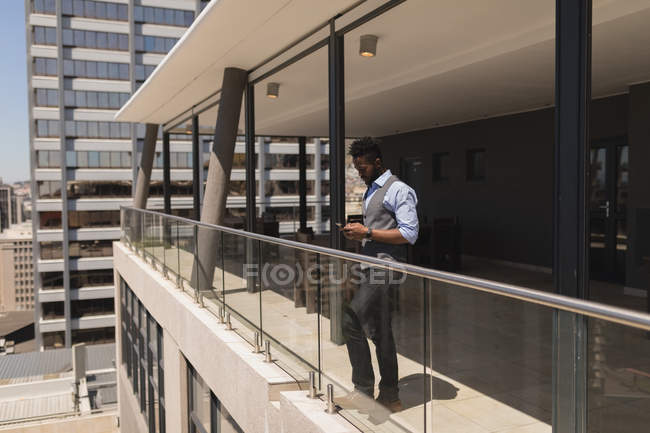 Geschäftsmann benutzt Handy auf Balkon im Büro — Stockfoto