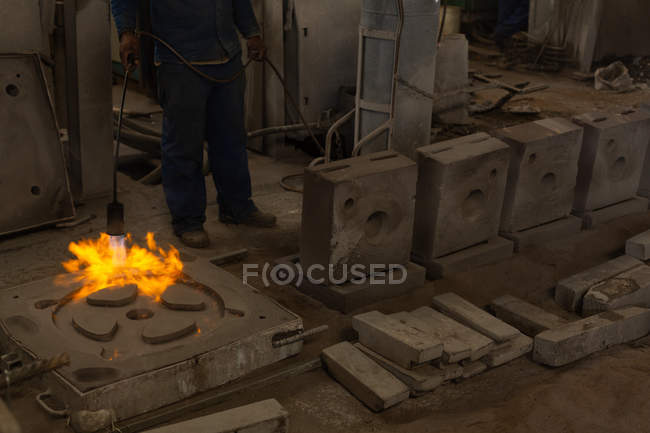 Baixa seção de fundição de metal de aquecimento do trabalhador com tocha flamejante — Fotografia de Stock
