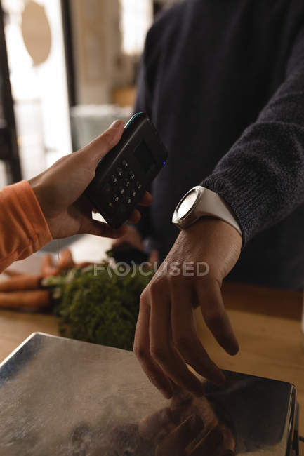 Cliente fazendo pagamento através de smartwatch no balcão no supermercado — Fotografia de Stock