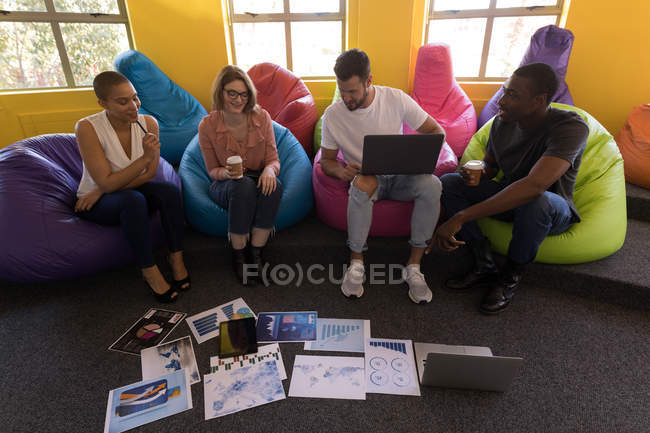 Business executives working while sitting on beanbag in office — Stock Photo