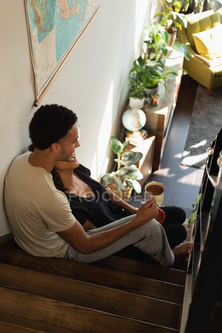 Couple interacting with each other while having coffee in stairs at home — Stock Photo