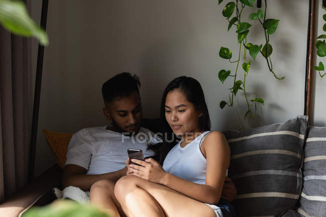 Paar benutzt Handy auf Sofa im heimischen Wohnzimmer — Stockfoto