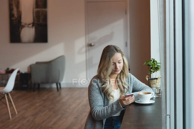 Beautiful woman using mobile phone in cafe — Stock Photo