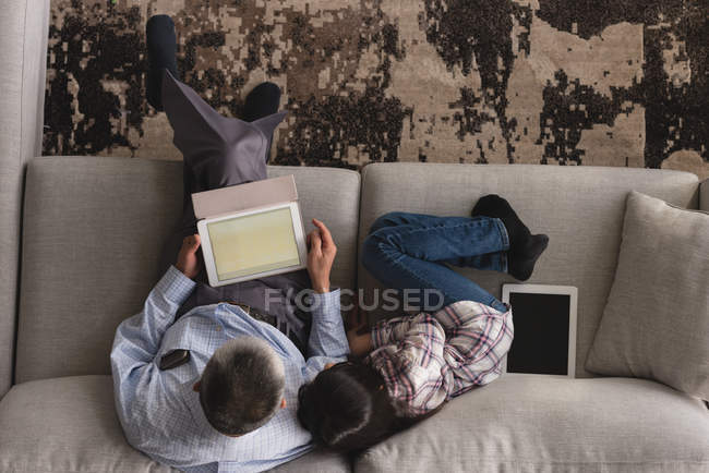 Overhead of grandfather and granddaughter using digital tablet on sofa in living room at home — Stock Photo