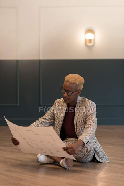 Inteligente hombre de negocios sosteniendo plano en la oficina - foto de stock