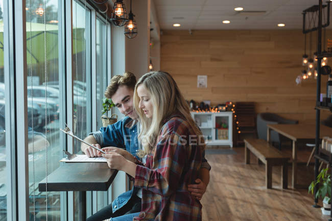 Paar diskutiert über Klemmbrett im Café — Stockfoto