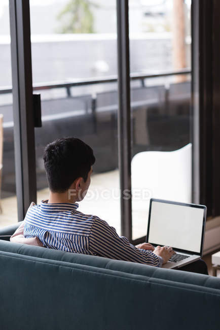 Вид сзади на мужчину с помощью ноутбука в офисе — стоковое фото