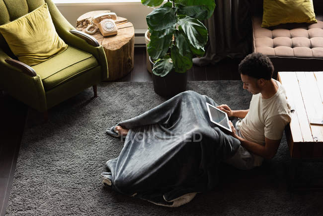 Uomo che utilizza tablet digitale in salotto a casa — Foto stock