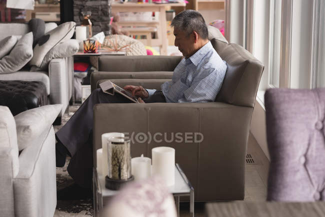 Вид збоку старший людини, що використовує цифровий планшетний у вітальні на дому — стокове фото