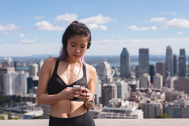 Бегунья слушает музыку на мобильном телефоне в солнечный день — стоковое фото