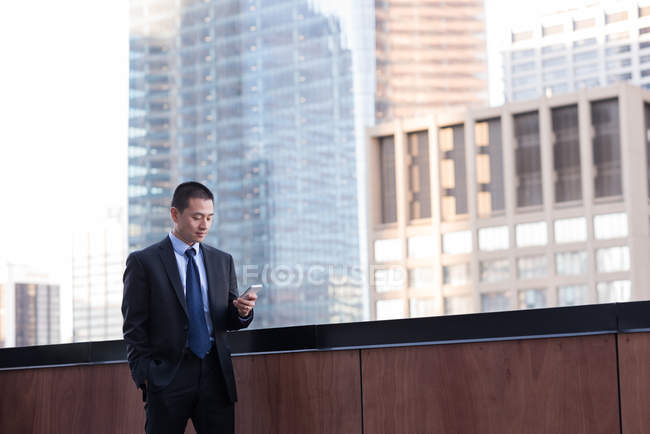 Uomo d'affari che utilizza il telefono cellulare in balcone in hotel — Foto stock