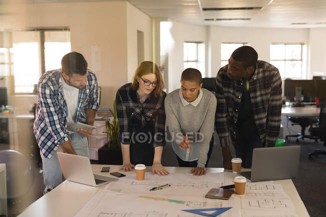 Business executives discussing over blueprint on table in office — Stock Photo