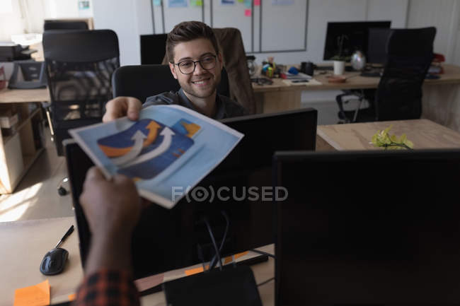 Усміхаючись чоловічого виконавчої даючи діаграми, щоб колега в офісі — стокове фото