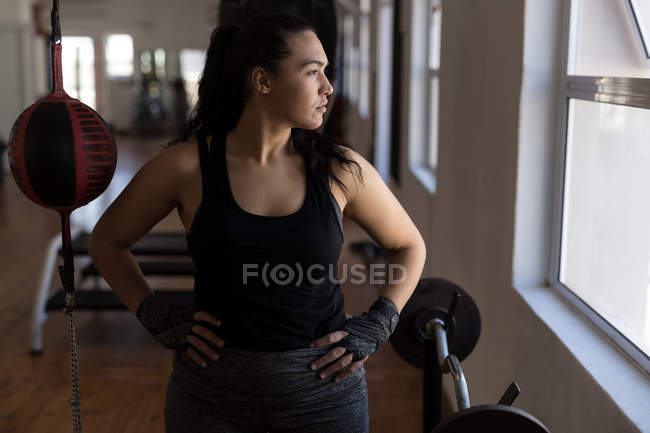Молода жінка-боксер дивиться через вікно у фітнес-студії — стокове фото