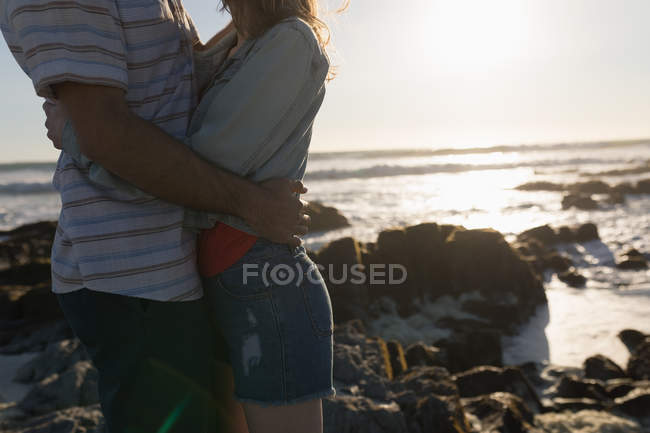 Parte centrale della coppia che si abbraccia sulla spiaggia — Foto stock