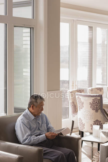 Homem sênior usando tablet digital na sala de estar em casa — Fotografia de Stock