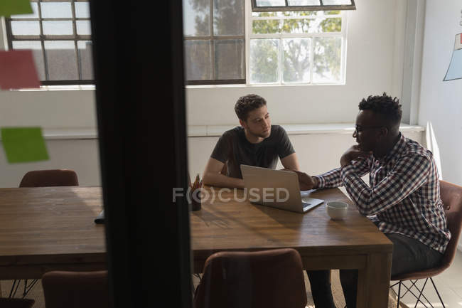 Executives discussing over laptop in conference room at office — Stock Photo