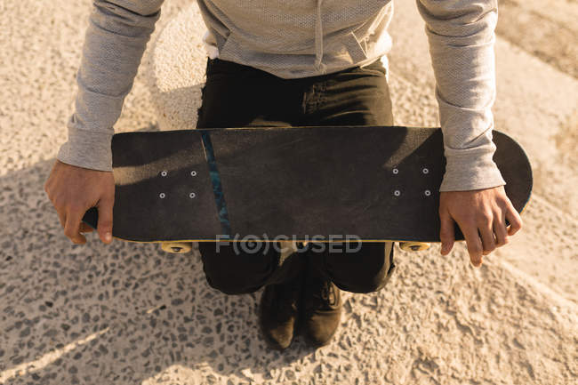 High angle view of woman sitting with skateboard on beach — Stock Photo