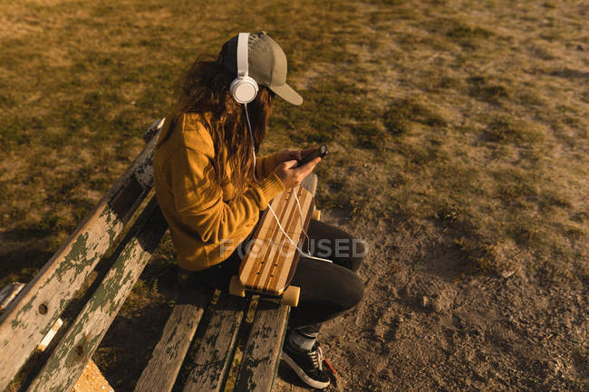 Молодая женщина слушает музыку на мобильном телефоне на пляже — стоковое фото