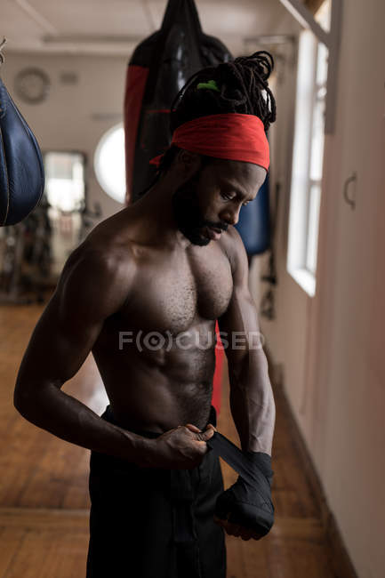 Young male boxer wearing hand wrap in fitness studio — Stock Photo