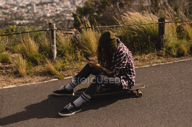 Jeune skateboarder utilisant un téléphone mobile — Photo de stock