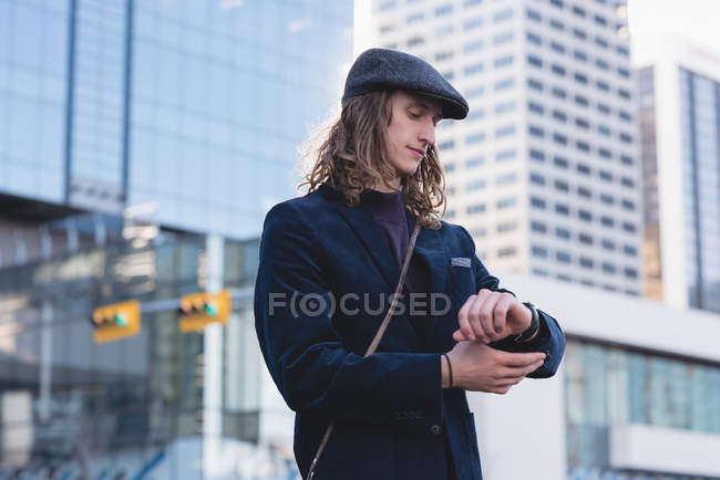 Mann kontrolliert beim Gassigehen in der Stadt die Uhrzeit — Stockfoto