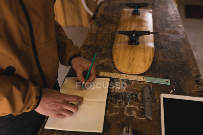 Close-up of man writing on notepad in workshop — Stock Photo
