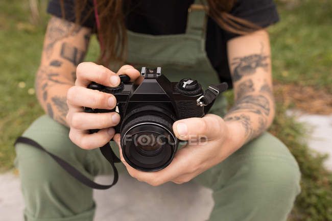 Close-up of woman sitting with digital camera in skateboard park — Stock Photo