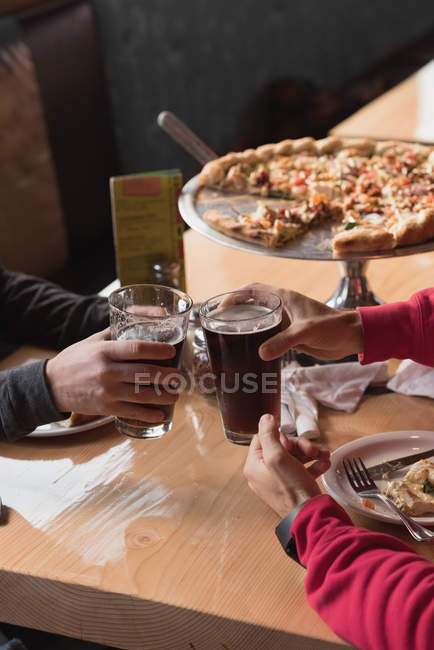 Close-up of friends toasting beer glasses in pub — Stock Photo