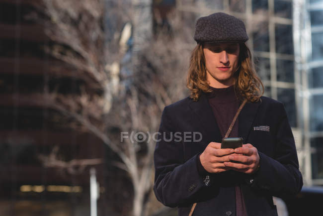 Человек с мобильного телефона во время прогулки по улице в городе — стоковое фото