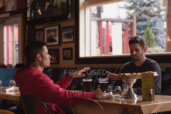 Amis parler entre eux tout en buvant un verre dans un pub — Photo de stock