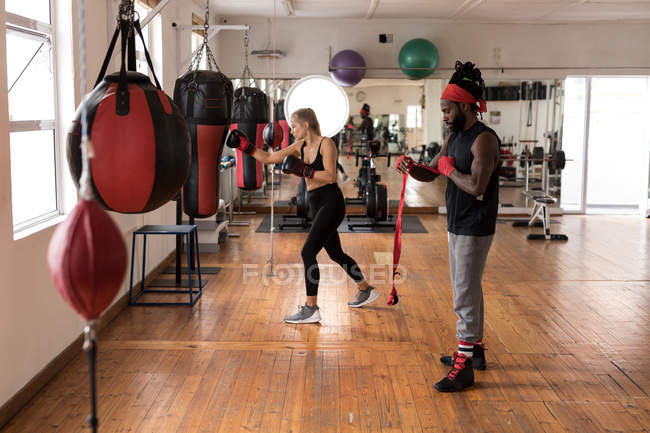 Boxeador joven masculino y femenino practicando en un gimnasio - foto de stock