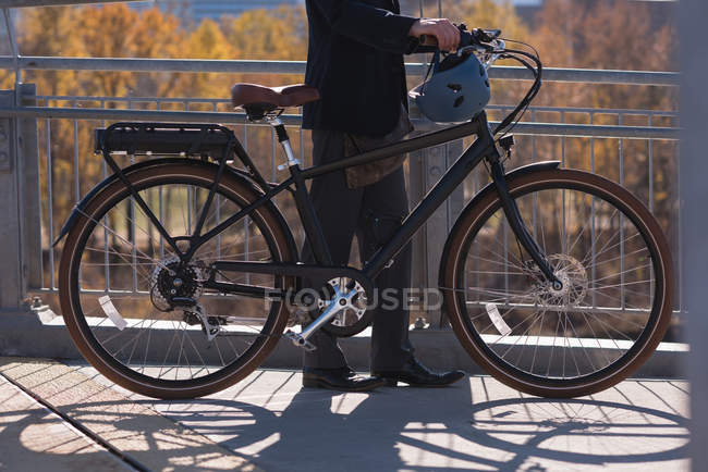 Низька частина людини, що стоїть з велосипедом на мосту в місті — стокове фото