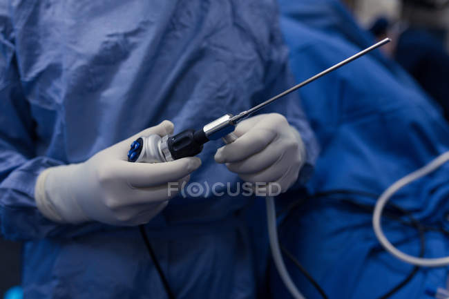 Средняя секция женского хирурга, держащего в больнице медицинский инструмент — стоковое фото