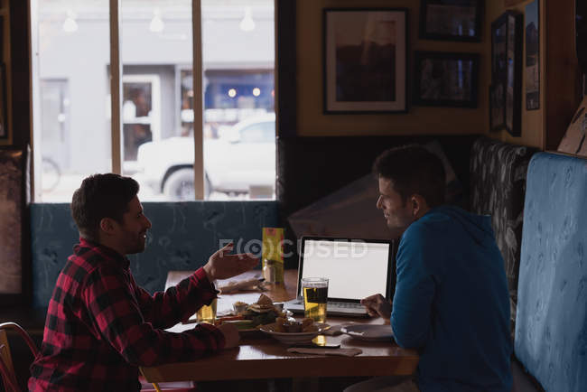 Friends discussing over laptop while having drinks at pub — Stock Photo