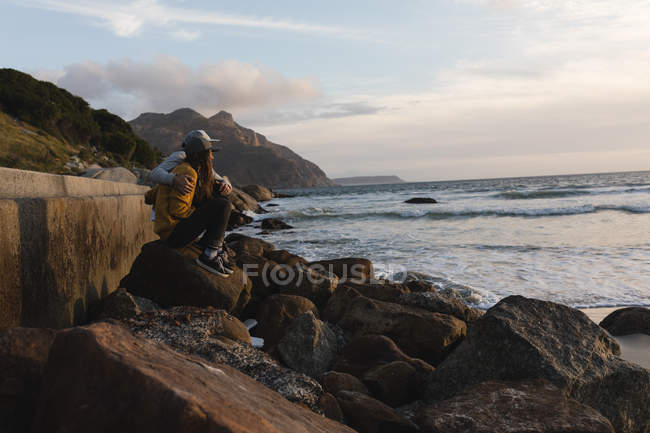 Pareja romántica sentada en roca cerca de la playa - foto de stock