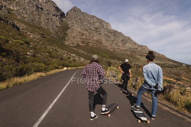 Vue arrière des skateboarders debout avec des skateboards en descente — Photo de stock