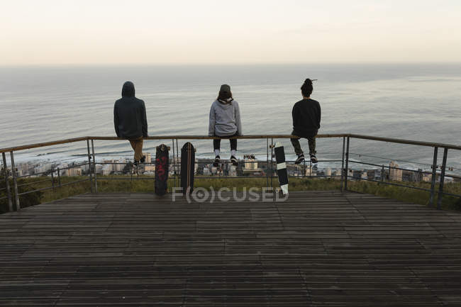 Rückansicht von Skateboardern, die auf einem Geländer am Aussichtspunkt sitzen — Stockfoto