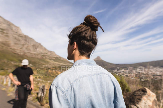 Rear view of skateboarder standing on downhill at countryside — Stock Photo