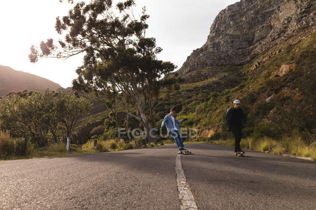Skateboarders skating on downhill at countryside on a sunny day — Stock Photo