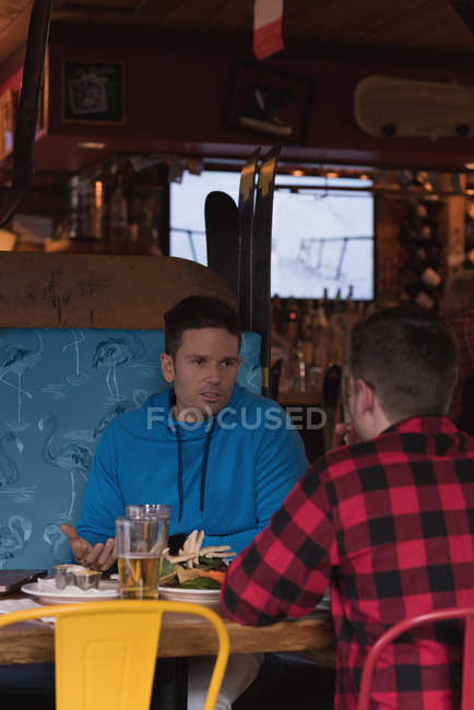 Friends talking with each other while having drinks in pub — Stock Photo