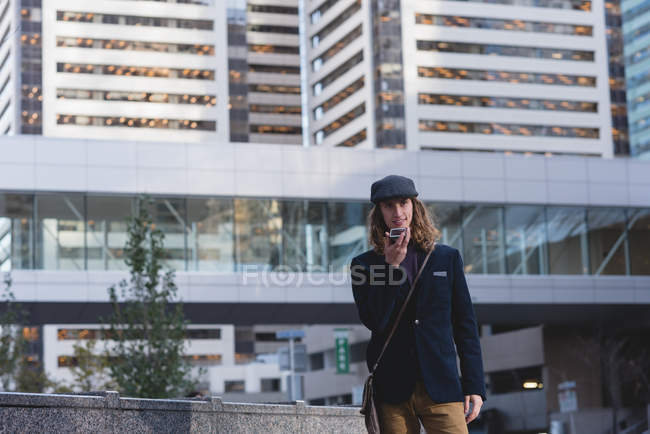 Man talking on mobile phone while walking on the street in the city — Stock Photo